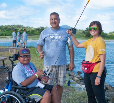 Camper smiling with support staff member and activity leader after catching a fish on the bay. Photo by: Beyond Memory Photography