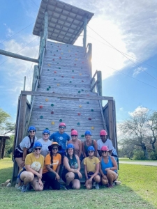 Camp Aranzazu activity leader gather together with their instructor in front of the rock wall