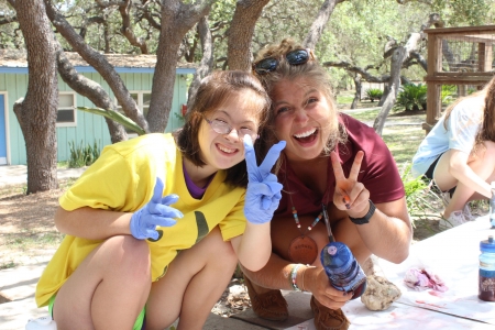 Camper and Amelia make peace sign with fingers and smile at camera during t-shirt tie-dying