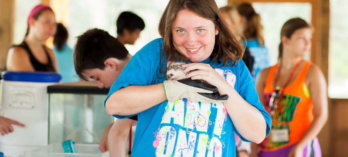 Little girl smiling and holding baby hedgehog while at Camp Aranzazu's nature hut.